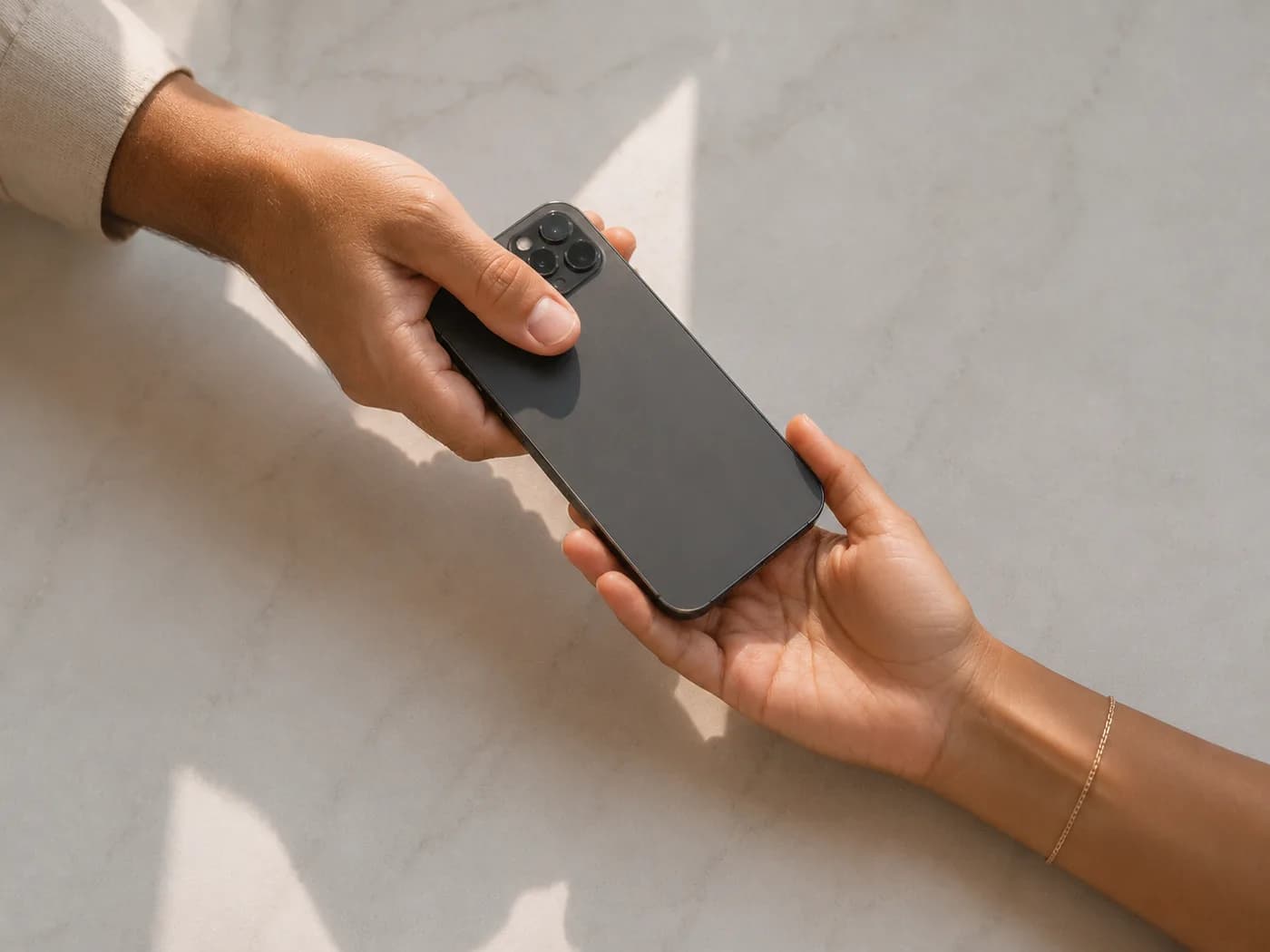 Dos personas intercambiando un celular sobre una mesa